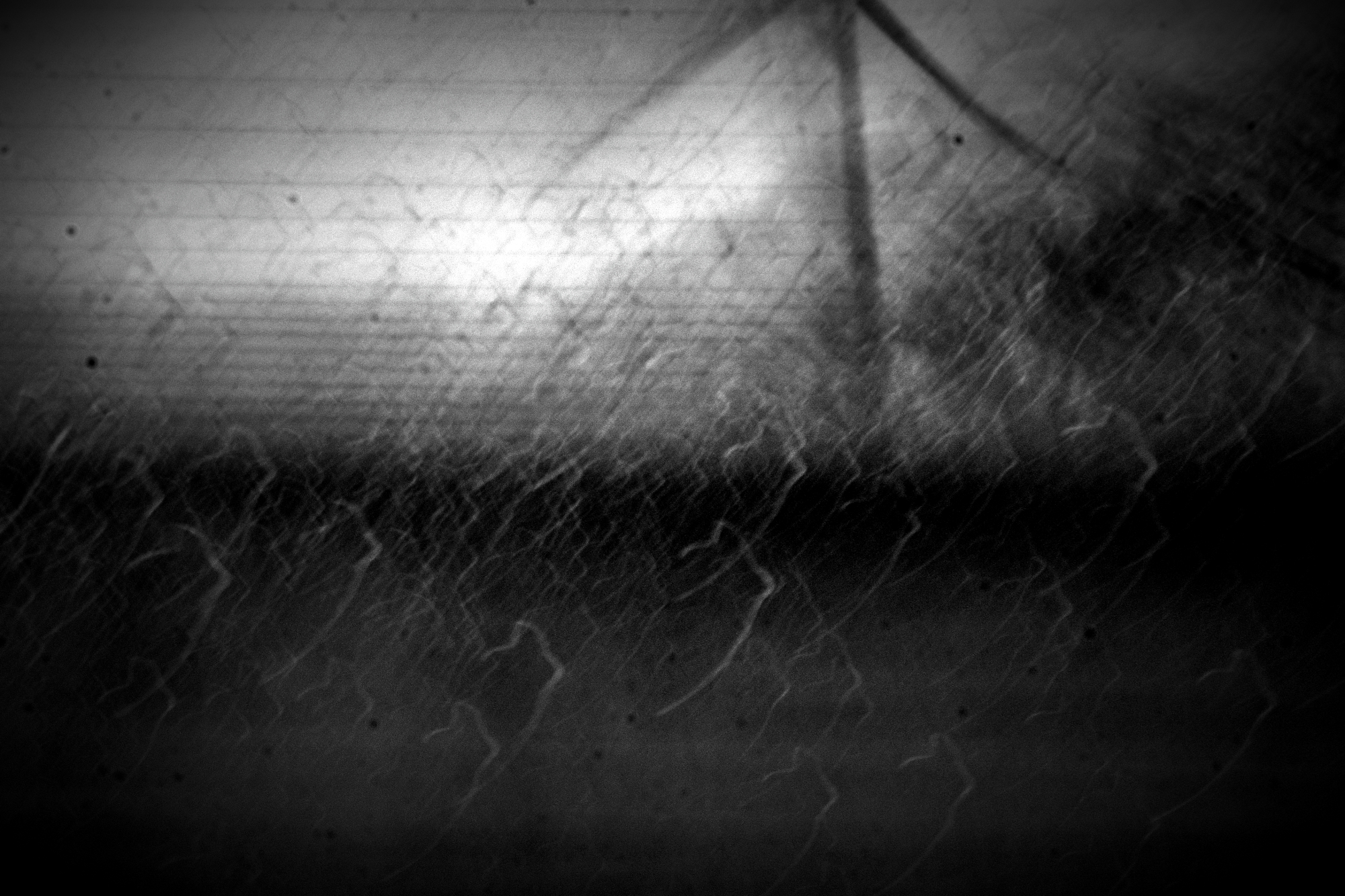 Foto durch ein Autofenster. Bewegungsunschärfe mit zerlaufenen Regentropfen. Im Hintergrund ein Windrad. Alles kaum zu erkennen. Sehr absttrakt. schwarz - weiß