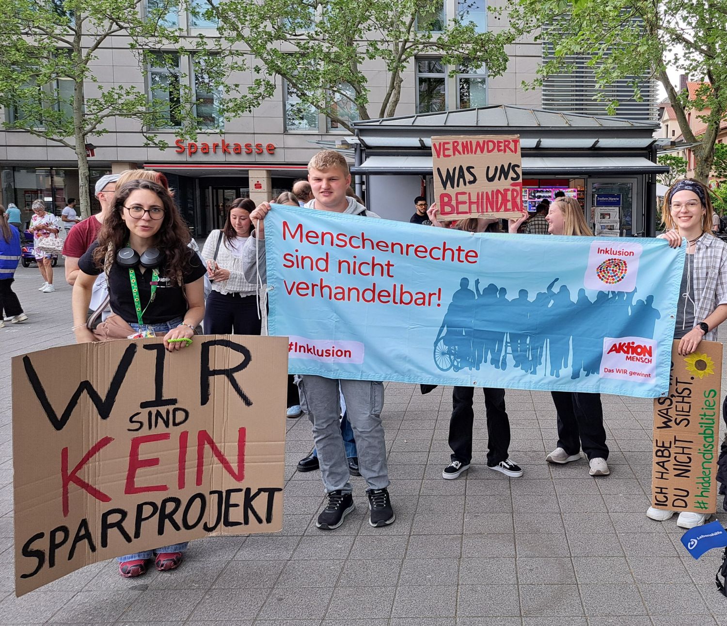 Mehrere Personen mit Transparenten mit Texten in welchen keine Einsparungen gefordert wird