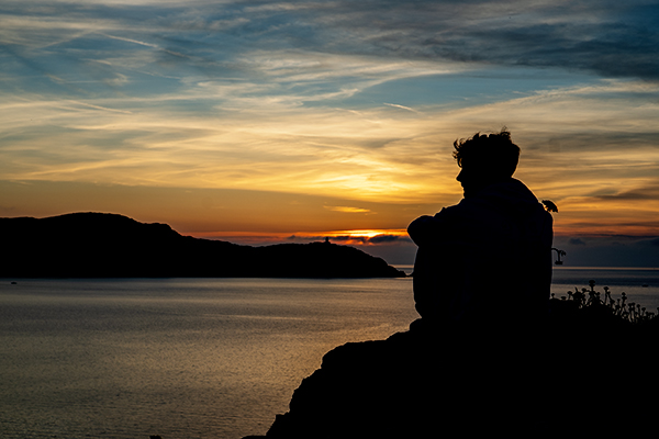 Der Umriss eine Menschen vor dem Hintergrund eines Sonnenuntergangs am Meer