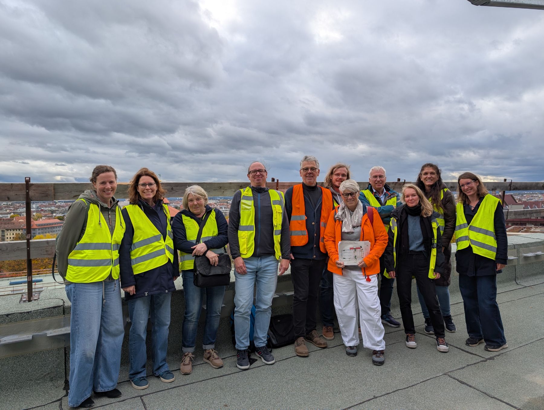 Gruppe von Männern und Frauen in Arbeitskleidung und mit Sicherheitsvesten