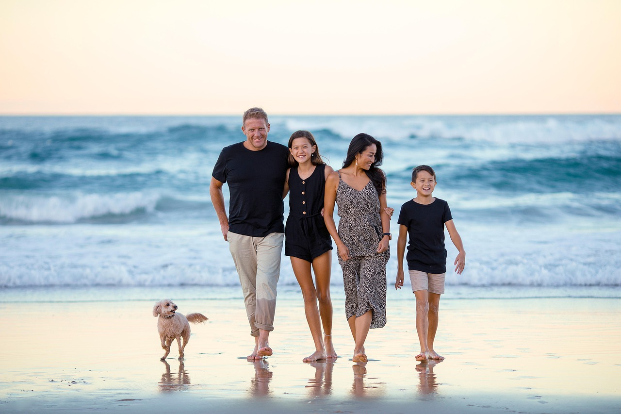 Familie mit zwei Kindern und einem Hund am Strand