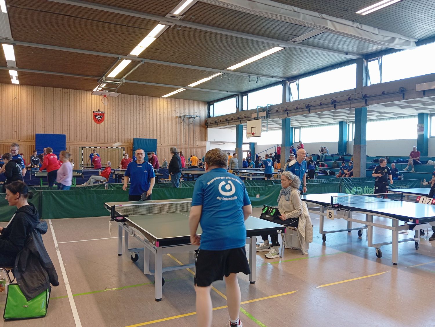 Sporthalle in welcher an mehreren Platten Tischtennis gespielt wird
