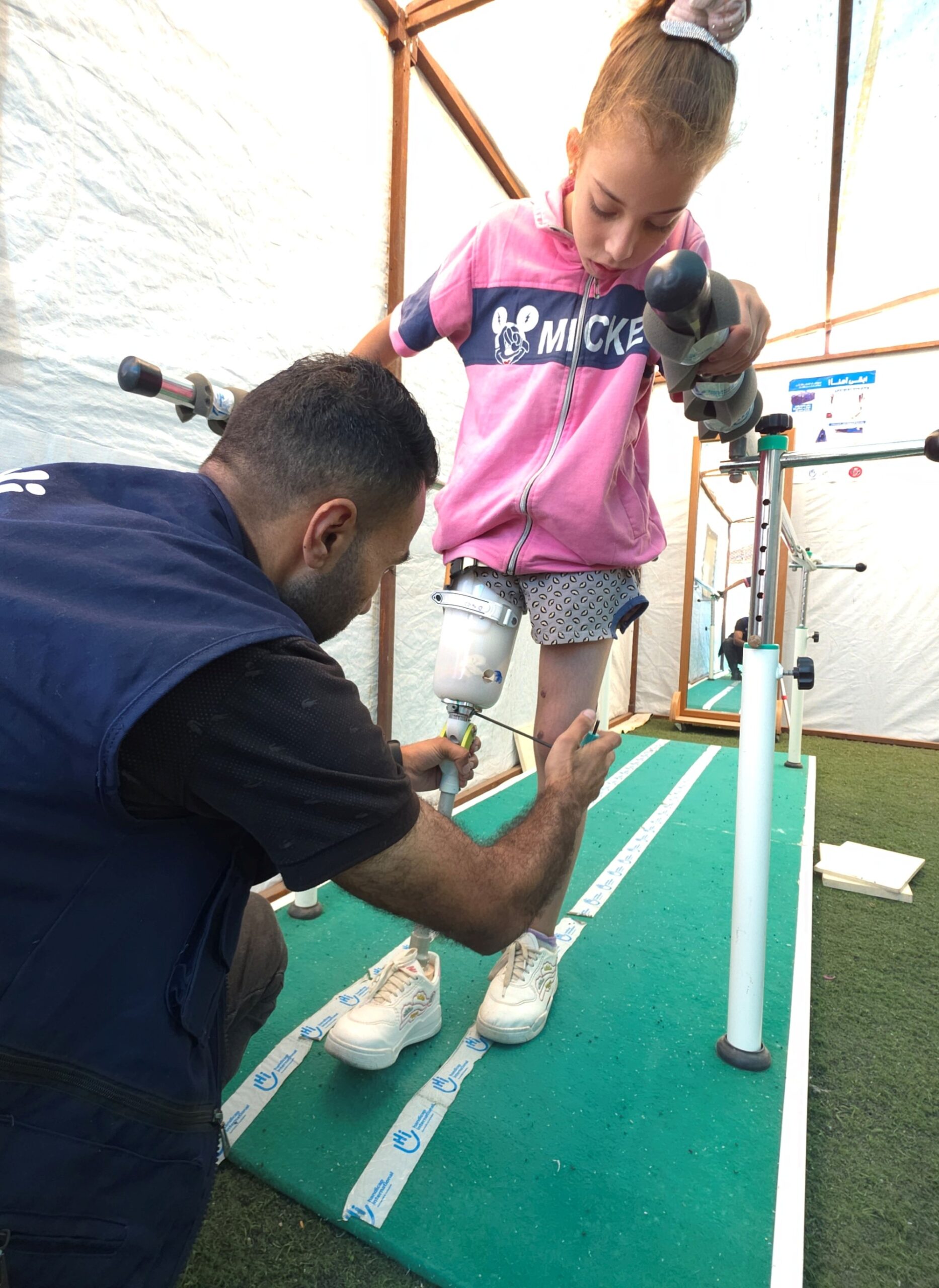 Ein kleines Mädchen werden auf einem Laufsteg durch einen Orthopäden Prothesen angepasst
