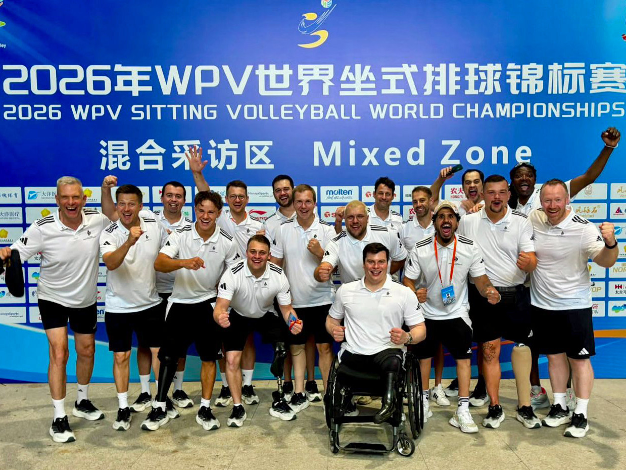Große Gruppe von Sportlern in dunkler Hose und mit weißem Hemd bekleidet vor einer blauen Wand mit der Aufschrift zur Weltmeisterschaft in chinesischer und englischer Sprache