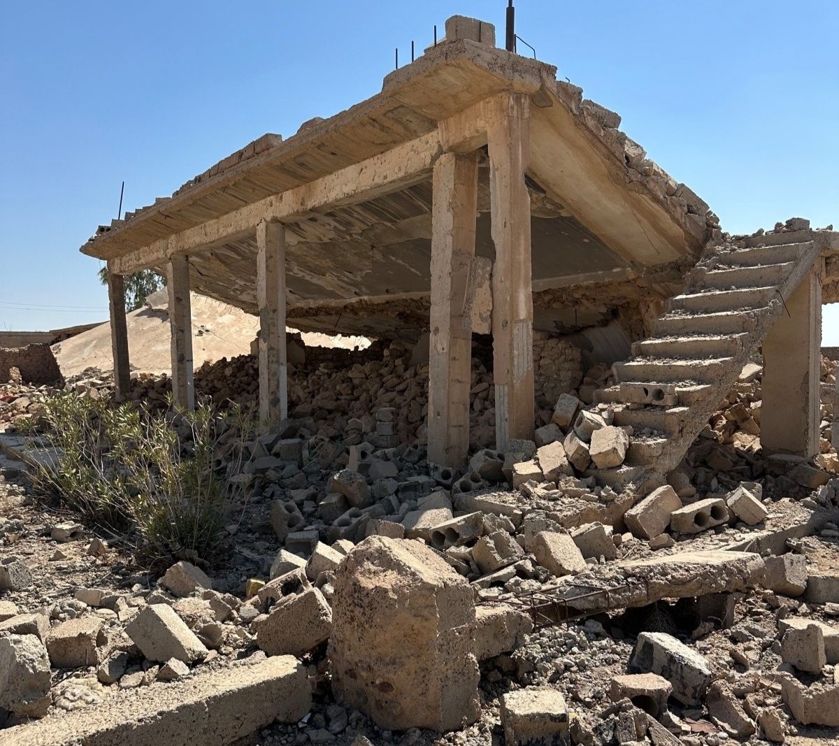 Blick auf den Eingang eines zerstörten Gebäudes mit einer von Trümmern verschütteten Treppe