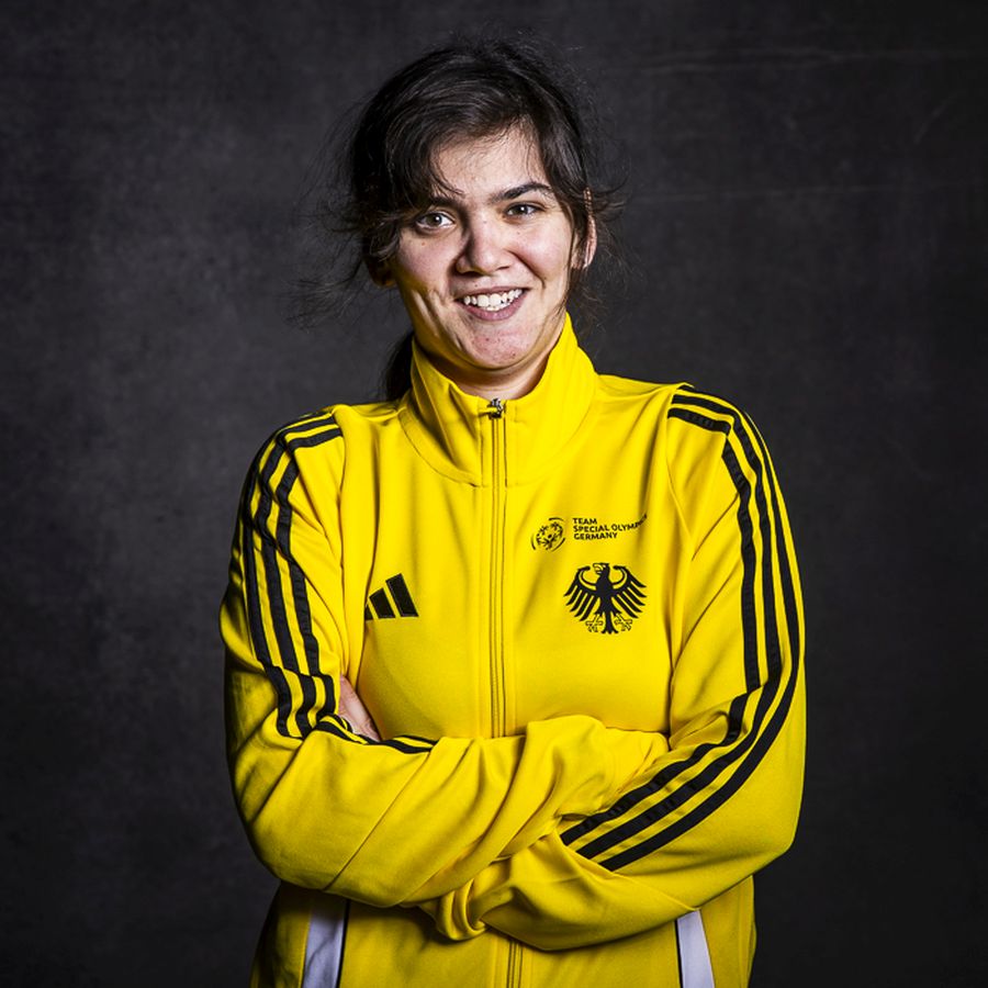 Junge Frau mit dunklen Haaren in gelber Sportjacke mit Bundesadler und schwarzen Streifen